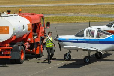 Cardiff Wales Airport, Galler - Temmuz 2018: Havaalanı önlüküzerinde park edilmiş yakıt tankeri ve Cardiff Wales Havaalanı'nda hafif bir uçağa yakıt ikmali yapmak üzere olan yakıt hortumu olan bir kişi