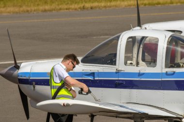 Cardiff Wales Airport, Galler - Temmuz 2018: Havaalanı önlüküzerinde park edilmiş yakıt tankeri ve Cardiff Wales Havaalanı'nda hafif bir uçağa yakıt ikmali yapmak üzere olan yakıt hortumu olan bir kişi