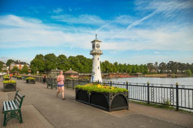 Cardiff, Galler - Ağustos 2018: Cardiff'teki Roath Park Gölü'nün manzara manzarası. Deniz feneri, Cardiff'i Güney Kutbu'na yaptığı gezide terk eden Kaptan Scott'ın anısına dikilir.