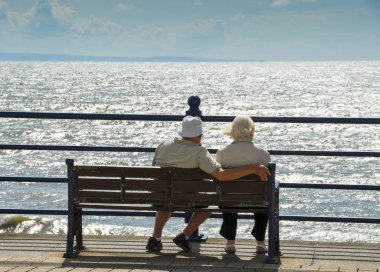 Porthcawl, Galler - Ağustos 2018: Yaşlı erkek ve kadın Porthcawl sahilinde bir koltukta oturan 