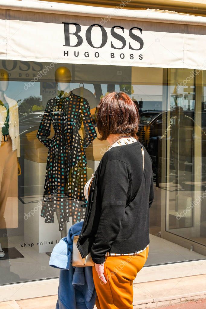 CANNES, FRANCE - APRIL 2019: Person looking in the window of the Hugo Boss store on the seafront in Cannes.