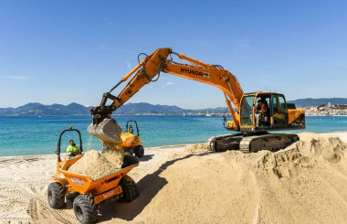 Cannes, Fransa - Nisan 2019: Cannes'daki plajı geliştirmek için kullanılan bir çöplük turuna kum bırakan bir ekskavatör kovası ilkbahar ve yaz tatili sezonuna hazır