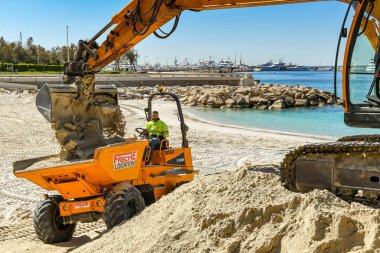 Cannes, Fransa - Nisan 2019: Cannes'daki plajı geliştirmek için kullanılan bir çöplük turuna kum bırakan bir ekskavatör kovası ilkbahar ve yaz tatili sezonuna hazır