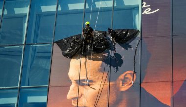 Cannes, Fransa - Nisan 2019: Binanın cam panellerinden plastik reklam istifini kaldırmak için Cannes'daki Palais des Festivalleri'nin yanından inen uzman bakım ekibi.