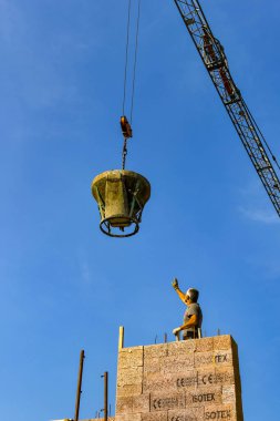 Garda, Garda Gölü, İtalya - Eylül 2018: Garda Gölü'ndeki Garda kasabasındaki bir şantiyede ağır çelik bir kova beton düşürmek için bir işçi tarafından kule vinç yönlendiriliyor.