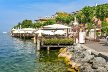 Torri Del Benaco, Garda Gölü, İtalya - Eylül 2018: Torri del Benaco'daki Garda Gölü'nün kenarındaki gezinti yolundaki restoranlarda güneş gölgelikleri içeren açık yemek alanları