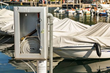 Garda, Garda Gölü, İtalya - Eylül 2018: Garda Gölü'ndeki Garda limanının kenarındaki metal bir kutuda yangın hortumu.