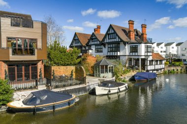 MARLOW, ENGLAND - MARCH 2019: Modern homes on the banks of the River Thames in Marlow with boat moorings. clipart