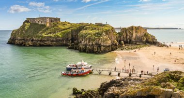 Tenby, Pembrokeshire, Galler - Ağustos 2018: Castle Beach ve St Catherine's Island Tenby, düşük tide, Batı Galler geniş açı görünümü. Küçük gemiyle gezmek sandal geçici bir iskelesi yanında kapalı ziyaretçilerin.
