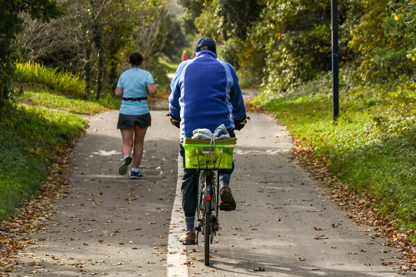 SWANSEA, WALES - OCTOBER 2018: People cycling and jogging on the coastal path from Mumbles to Swansea