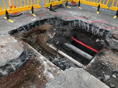 Pontypridd, Galler - Haziran 2019: Gaz borununa yeni bir vana takmak için yola büyük bir hendek kazıldı. Vanasız mevcut gaz boruları ve diğer yardımcı boru lar ve kablolar yol yüzeyinin altında görülebilir.