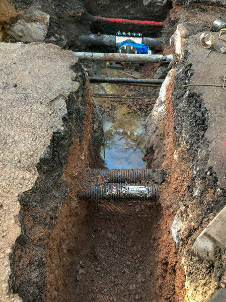 ПОНТИПРД, ИЮНЬ 2019: Большая траншея, вырытая в дороге для установки нового клапана в газопроводе. Другие трубы и кабели можно увидеть на переднем плане
.