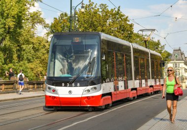 Prag, Çek Cumhuriyeti - Ağustos 2018: Prag'ın modern elektrikli tramvaylarından biri şehir merkezinde ki bir sokakta yürüyen insanların yanından geçiyor.