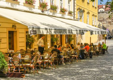 Prag, Çek Cumhuriyeti - Ağustos 2018: Prag'da bir restoranda dışarıdaki masalarda oturanlar.