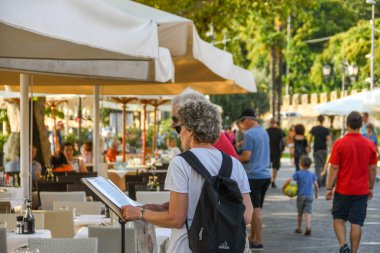 Garda, İtalya - Eylül 2018: Garda Gölü'ndeki göl kenarındaki bir restoranın menüsünde okuyan iki kişi.