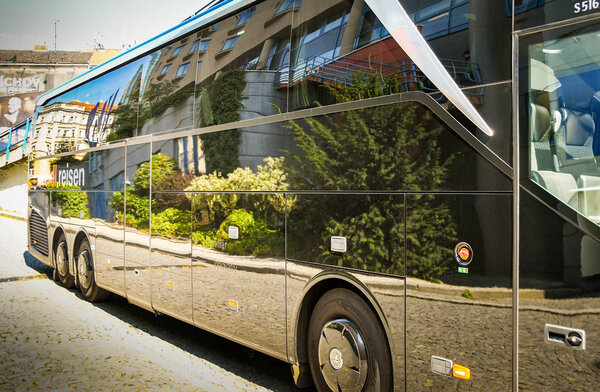 PRAGUE, CZECH REPUBLIC - JULY 2018: Luxury motor coach parked overnight in  Prague with the reflection of buidlings and bushes in its polished paintwork.