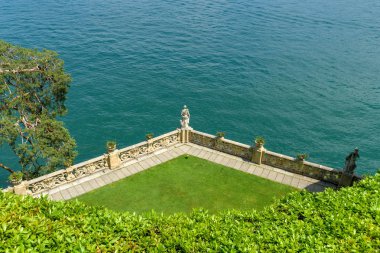 Lenno, Como Gölü, İtalya - Haziran 2019: Como Gölü'ndeki Lenno'daki Villa Balbianello'da çim, duvar ve taş heykelli teras.