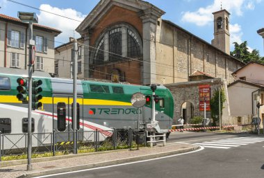 Como, İtalya - Haziran 2019: Como Gölü'ndeki Como kasabasından hareket eden modern elektrikli tren, bir karayolu geçidinden geçiyor