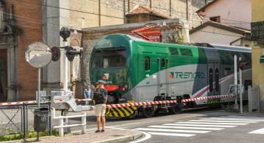 Como, İtalya - Haziran 2019: Como Gölü'ndeki Como kasabasından hareket eden modern elektrikli tren, bir karayolu geçidinden geçiyor