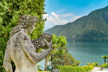 Lenno, Como Gölü, Italya-Haziran 2019: arka planda Como Gölü ile Lenno Villa Balbianello gerekçesiyle taş heykel.