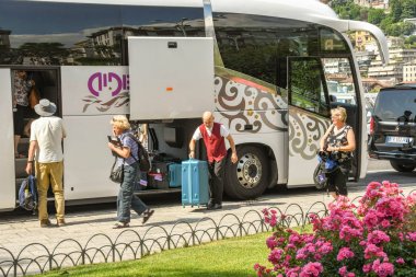 Como, Como Gölü, İtalya - Haziran 2019: Como Gölü'ndeki Como kasabasında bir otobüsten inen insanlar. Otel personelinin bir üyesi bagaj boşaltıyor.