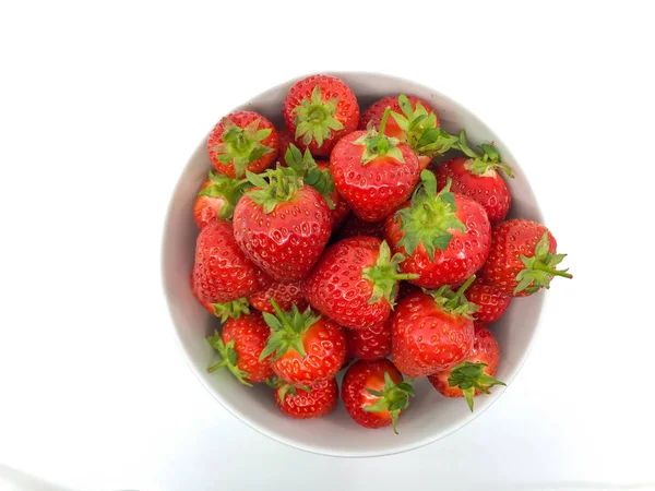 Düz beyaz arka planda beyaz bir kase tombul Olgun taze çilek.