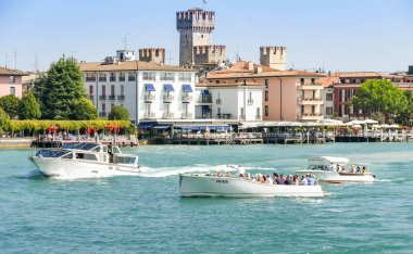 Garda Gölü, İtalya - Eylül 2018: Garda Gölü'ndeki göl kenarındaki binaların önünde sakin suüzerinde motorlu kruvazör ve tekneler