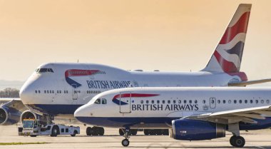 Londra, İngiltere - Mart 2019: British Airways Airbus A319 jeti Londra Heathrow Havaalanı'nda havayolunun Boeing 747 jumbo jetlerinden birini geçiyor.
