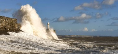 Porthcawl, Galler - Ekim 2018: Porthcawl, Galler'de gelgitte akşam güneş ışığında liman duvarına çarpan dalgalar.