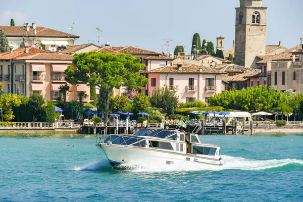 Garda Gölü, İtalya - Eylül 2018: Garda Gölü'ndeki göl kenarındaki binaların önünde hızla motorlu kruvazör