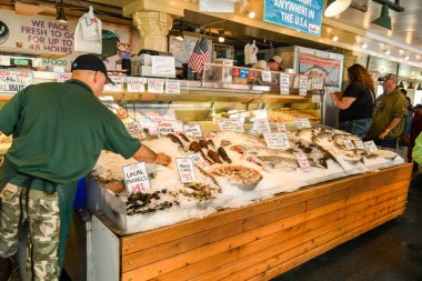Seattle, Washington State, ABD - Haziran 2018: Seattle şehir merkezindeki Pike Place Market'te taze balık sergilemeye bakan kişi.