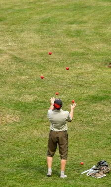 Bath, İngiltere - Temmuz 2019: Bath'ın santrifüsündeki Parade Gardens'ta kırmızı hokkabazlık toplarıyla pratik eden kişi.