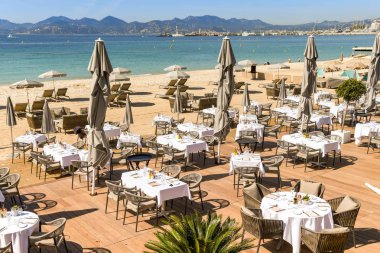 Cannes, Fransa - Nisan 2019: Cannes'da sahildeki bir restoranda masaların yer verdiği açık yemek alanı.