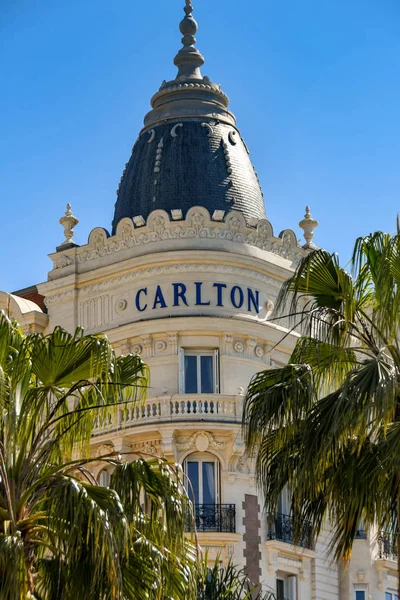Cannes, Fransa - Nisan 2019: Süslü Carlton Hotel'in köşesi palmiye ağaçlarıyla çevrilidir. Otel, Cannes'da deniz kıyısında bir dönüm noktasıdır..
