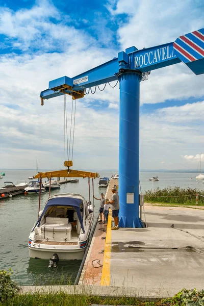 Bardolino, Garda Gölü, İtalya - Eylül 2018: Bardolino yakınlarındaki Garda Gölü'ndeki bir marinada bir motoru suya indiren vinç.