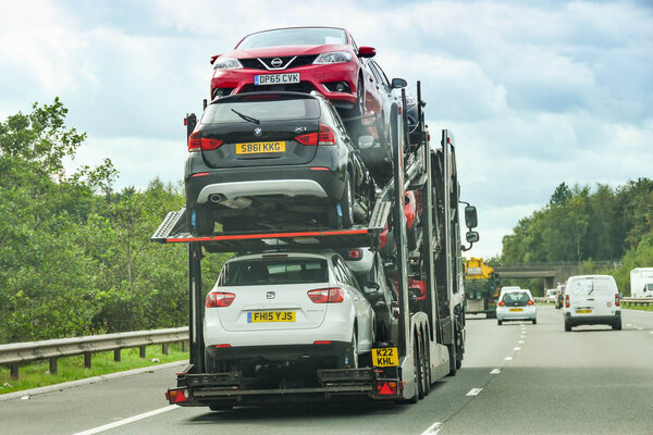 CARDIFF, WALES - СЕНТЯБРЬ 2018: Задняя часть автомобильного транспортера с полной загрузкой автомобилей на автомагистрали М4 возле Кардиффа
