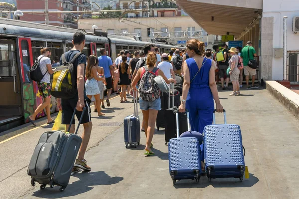 Sorrento, İtalya - Ağustos 2019: İnsanlar Sorrento tren istasyonuna vardıktan sonra bir platform boyunca bavul çekiyor.