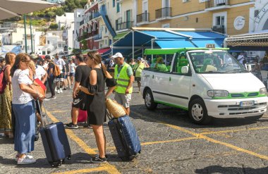 Isle Of Capri, İtalya - Ağustos 2019: Bir feribotla geldikten sonra Capri Adası'ndaki limanda taksi durağında bagajı olan kişiler.