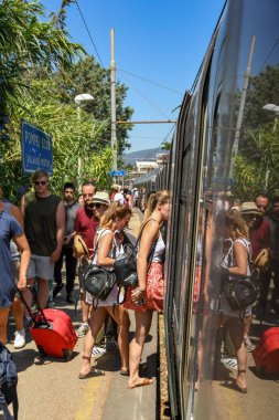 Pompeii, Napoli yakınlarında, İtalya - Ağustos 2019: Diğerleri çıkışa giden platform boyunca yürürken insanlar Pompeii Scavi istasyonunda trene biniyor