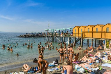 Sorrento, İtalya - Ağustos 2019: Küçük plajda ve kayalıkların üzerinde yer alan Sorrento kasabasının altındaki denizde insanlar.