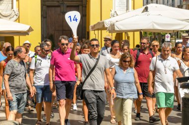 Sorrento, İtalya - Ağustos 2019: Sorrento sokaklarında yürüyüş turunda yolcu gemisi yolcularının tur partisine önderlik eden bir numaralı tabela tutan tur rehberi.