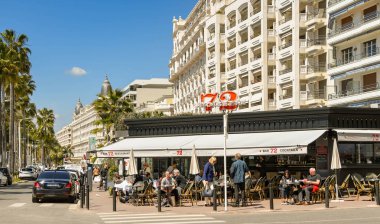 Cannes, Fransa - Nisan 2019: Cannes'da sahil yolundaki Bar 72 cafe restoranının dışındaki masalarda oturanlar