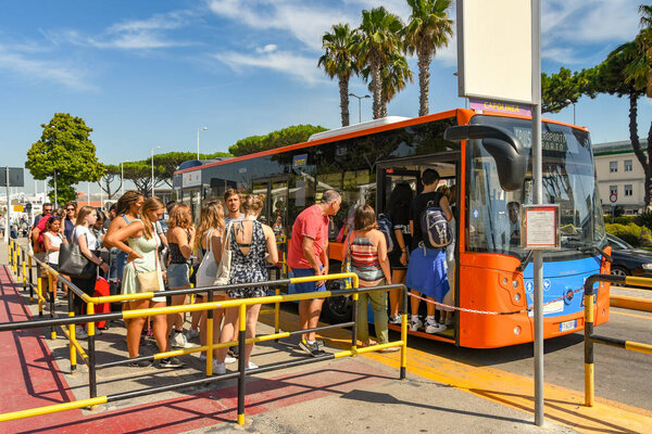 NAPLES , ITALY - AUGUST 2019: People queuing to get on a bus at Naples airport