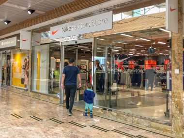 GLOUCESTER, ENGLAND - SEPTEMBER 2019: People entering the Nike factory store in the covered shopping centre in the Gloucester Quays development. clipart