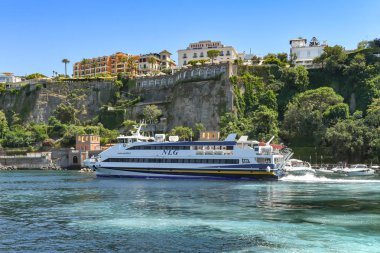 Sorrento, İtalya - Ağustos 2019: Arka planda kayalıklarla Sorrento'dan ve Europa Palace Grand Hotel'den ayrılan hızlı feribot.
