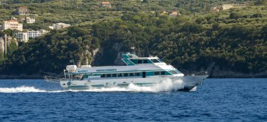 Sorrento, İtalya - Ağustos 2019: Hızlanırken motorlardan güçlü itme gücüyle Sorrento yakınlarındaki kıyı şeridini geçen hızlı feribot.