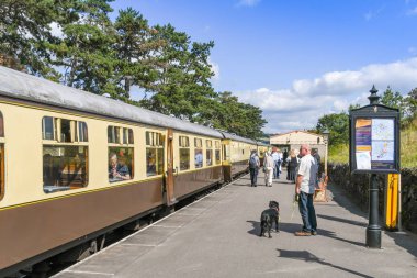 Cheltenham, İngiltere - Eylül 2019: Gloucestershire ve Warwickshire Buharlı Demiryolu'ndaki Cheltenham Hipodromu İstasyonu'nun platformundaki insanlar. İstasyonda bir tren var..