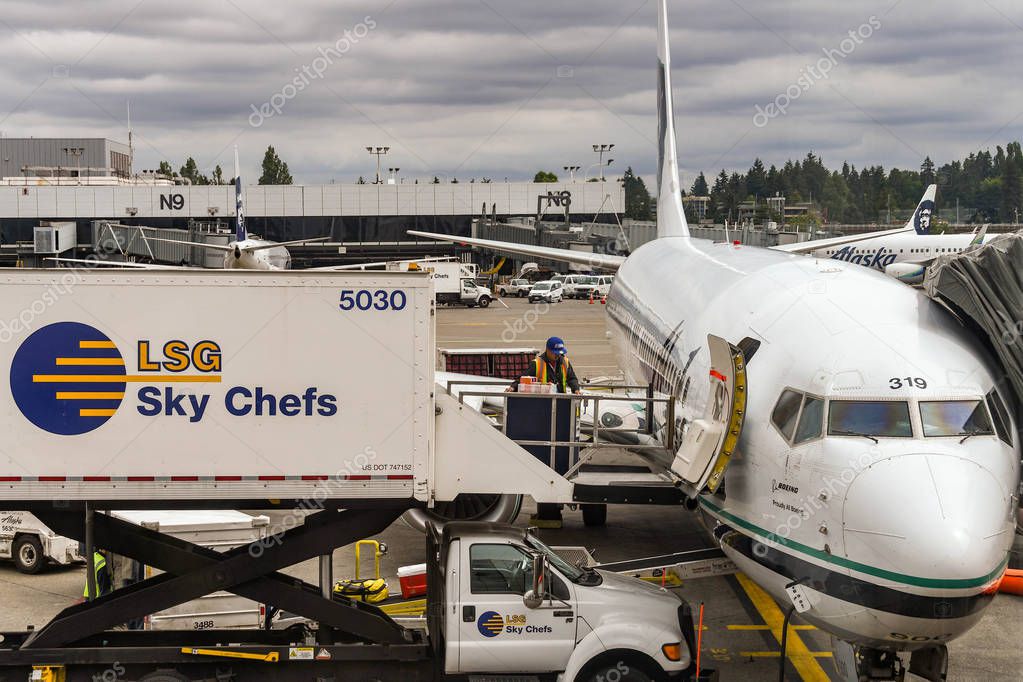 SEATTLE TACOMA AIRPORT, WA, USA - JUNE 2018: Close up view of an aiport worker loading food and other catering supplies from a LSG Sky Chefs hydraulic lift truck into an Alaska Airlines Boeing 737 jet at Seattle Tacoma airport.