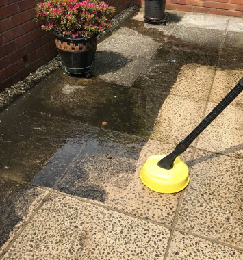 Cardiff, Galler - Mayıs 2018: Bir bahçe verandası üzerindeki beton levhaların basınç yıkama cihazıyla temizlenmesi için geniş açılı görünümü