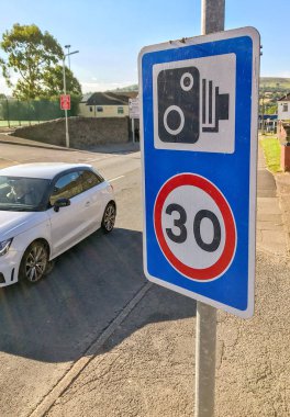 Pontypridd, Galler - Temmuz 2019: Pontypridd yakınlarındaki bir köyde sürücülerin saatte 30 mil hız limitini gösteren bir tabela. Tabelada bir trafik kamerası sembolü de var.